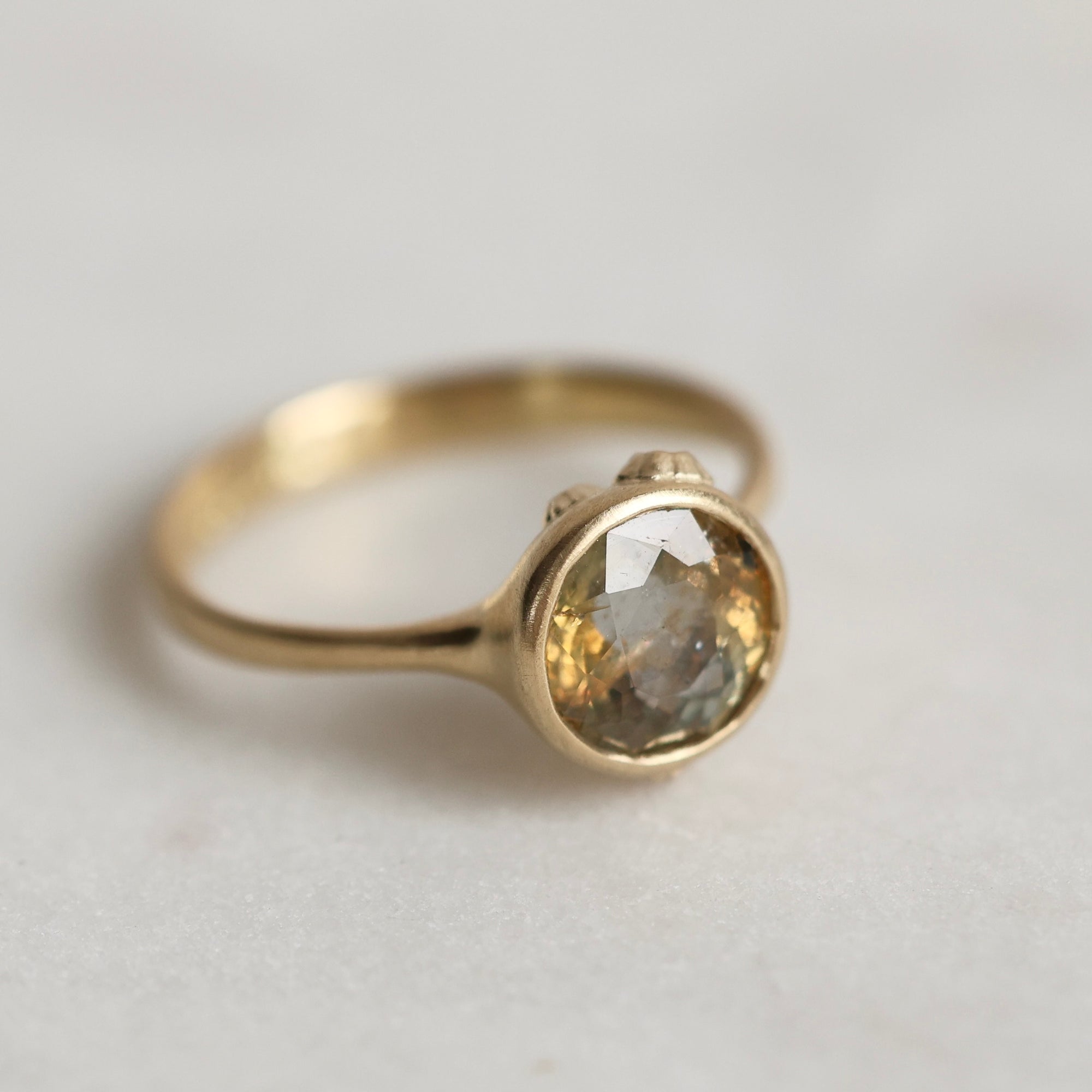 Gold ring with a gold sapphire on a light gray background
