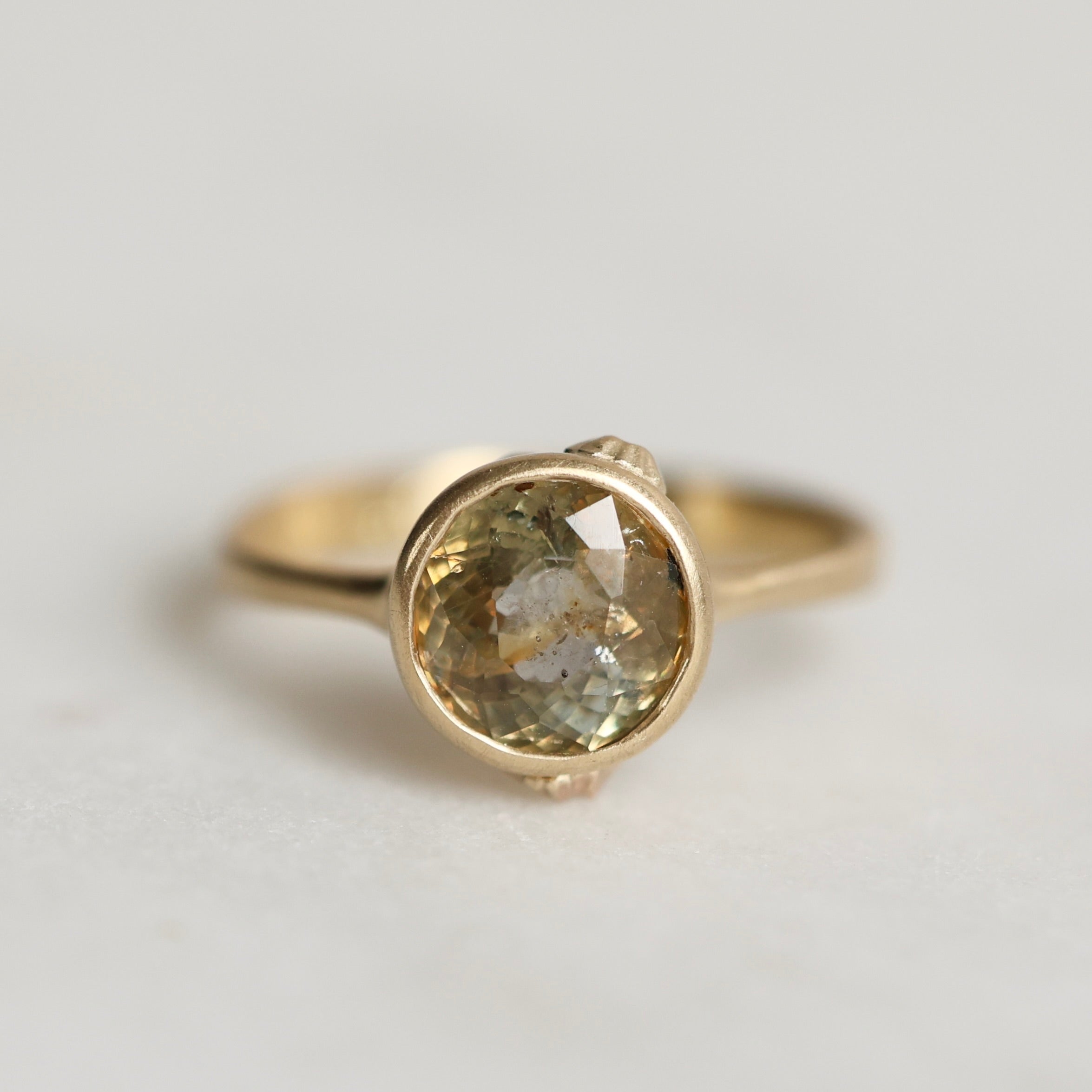 Gold ring with a gold sapphire on a light gray background