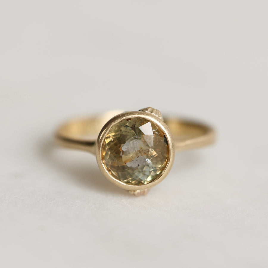 Gold ring with a gold sapphire on a light gray background