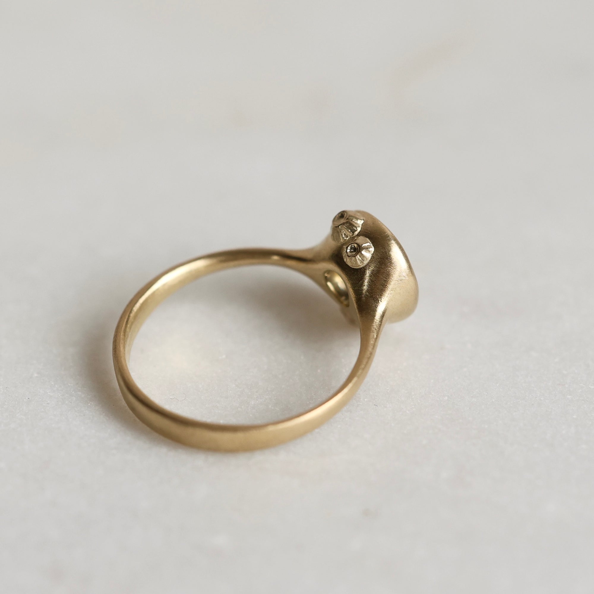 Gold ring with a gold sapphire on a light gray background