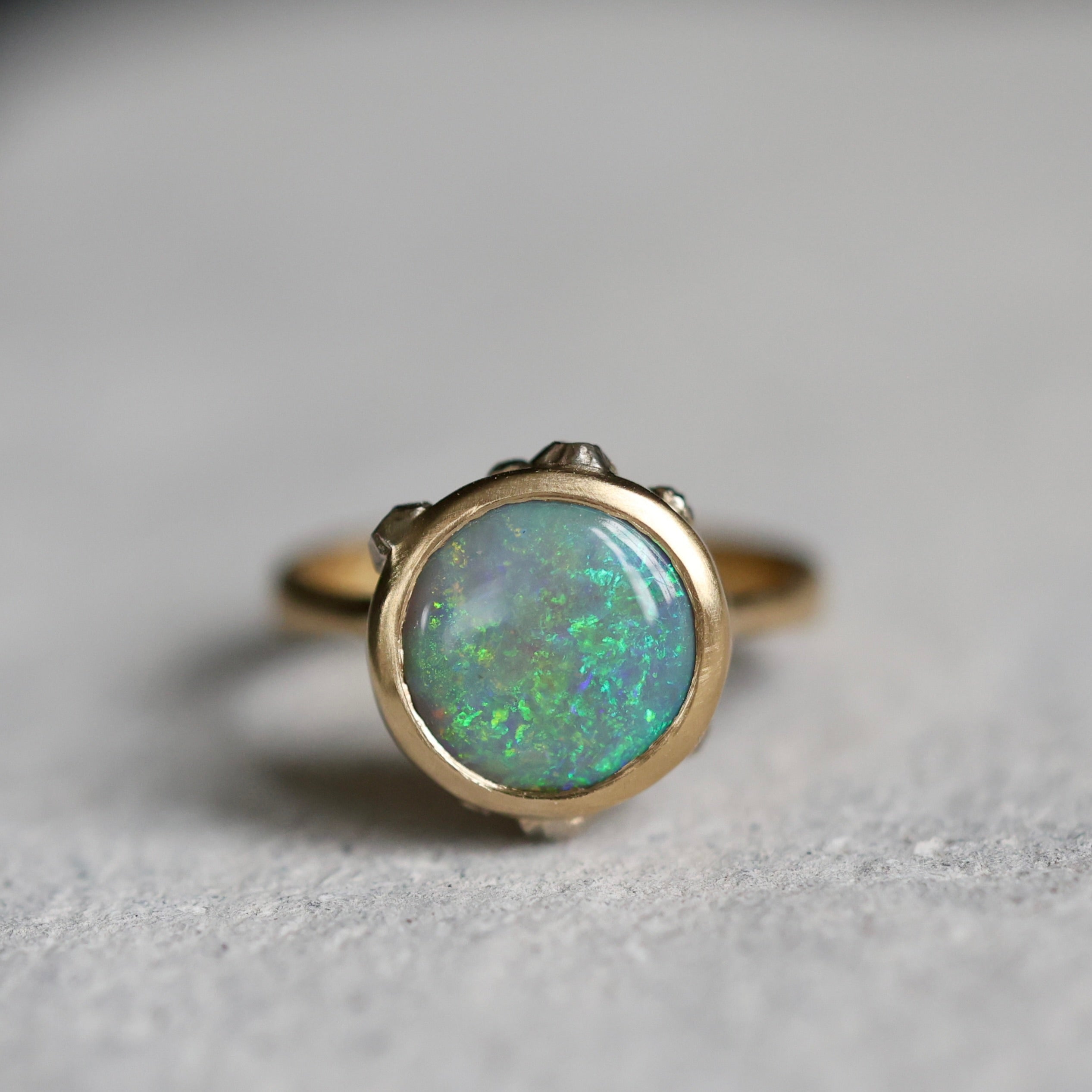 Gold ring with a green opal stone on a gray background