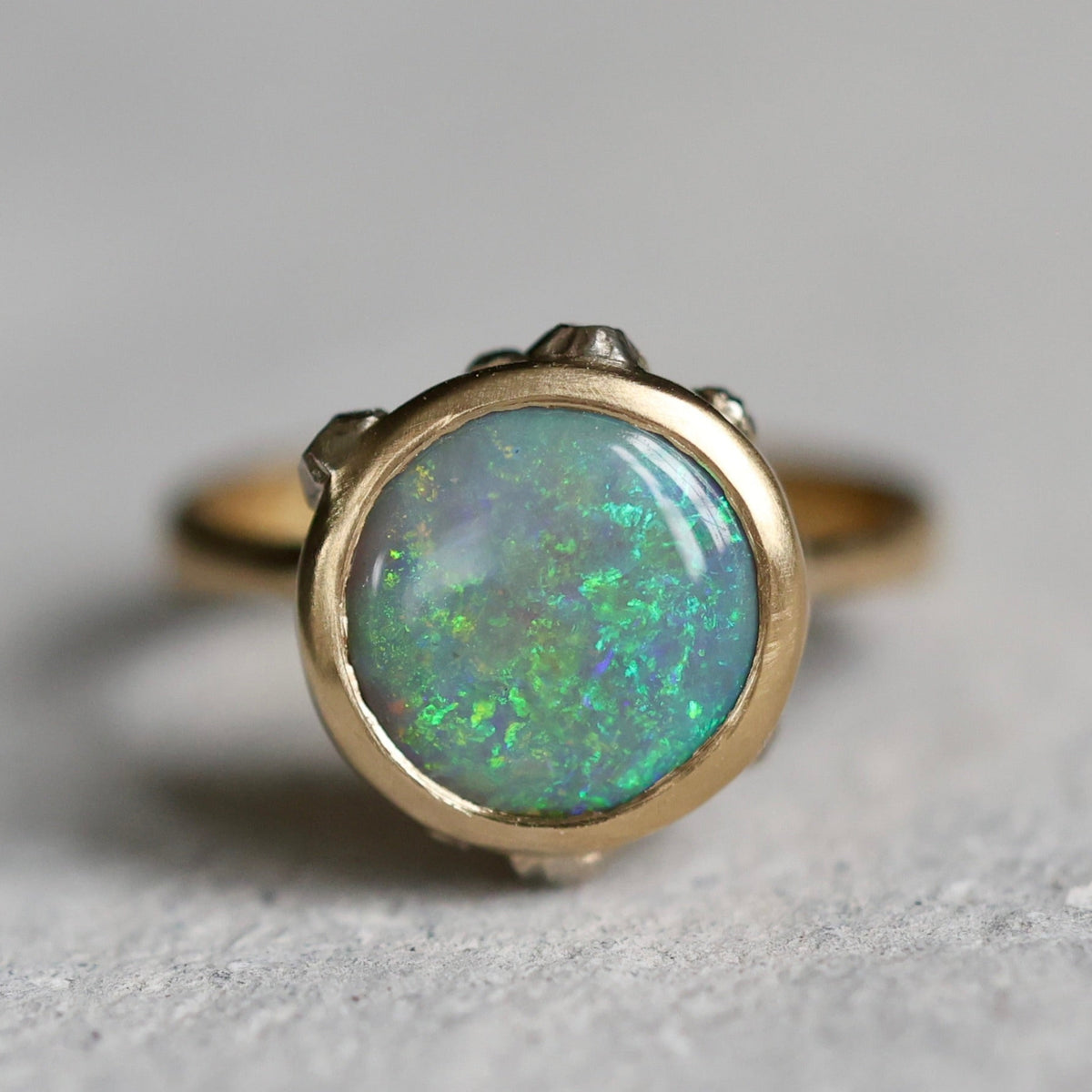 Gold ring with a green opal stone on a gray background