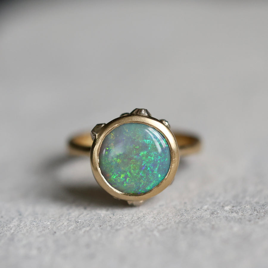 Gold ring with a green opal stone on a gray background