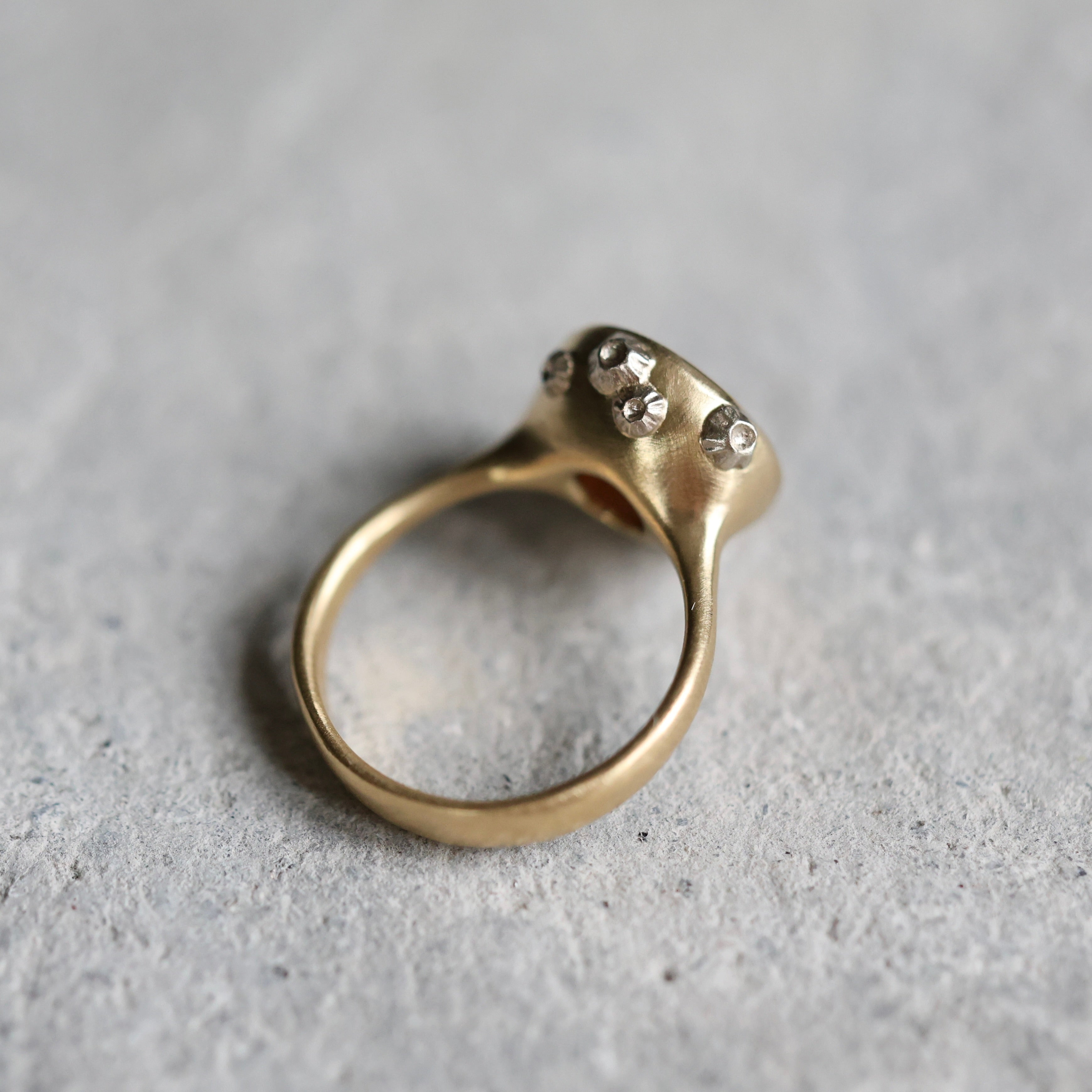 Gold ring with white gold barnacles on a gray surface