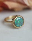Gold ring with a green opal on a light background