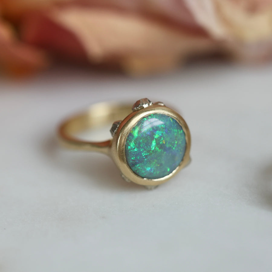 Gold ring with a green opal on a light background