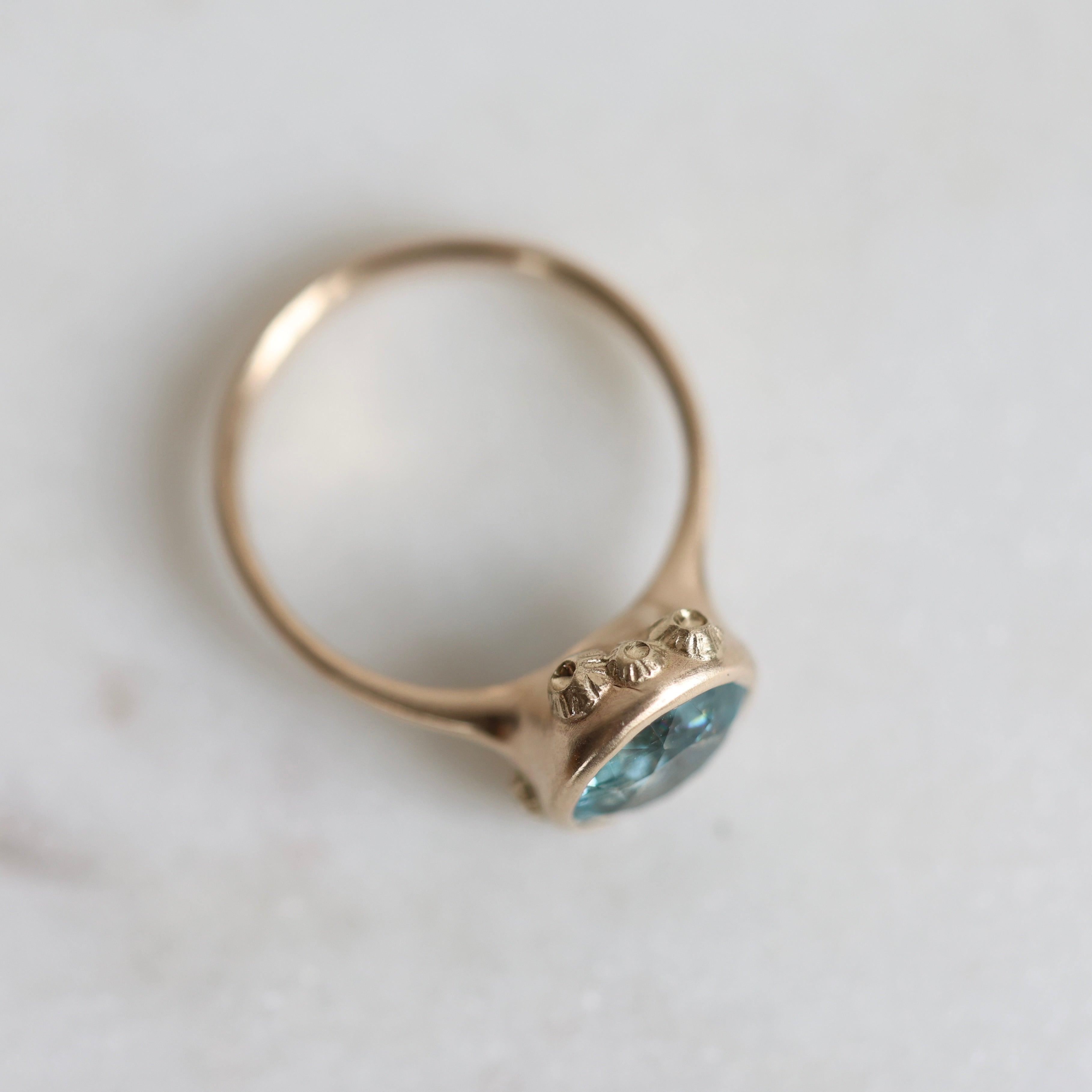 Gold ring with a blue gemstone on a light background