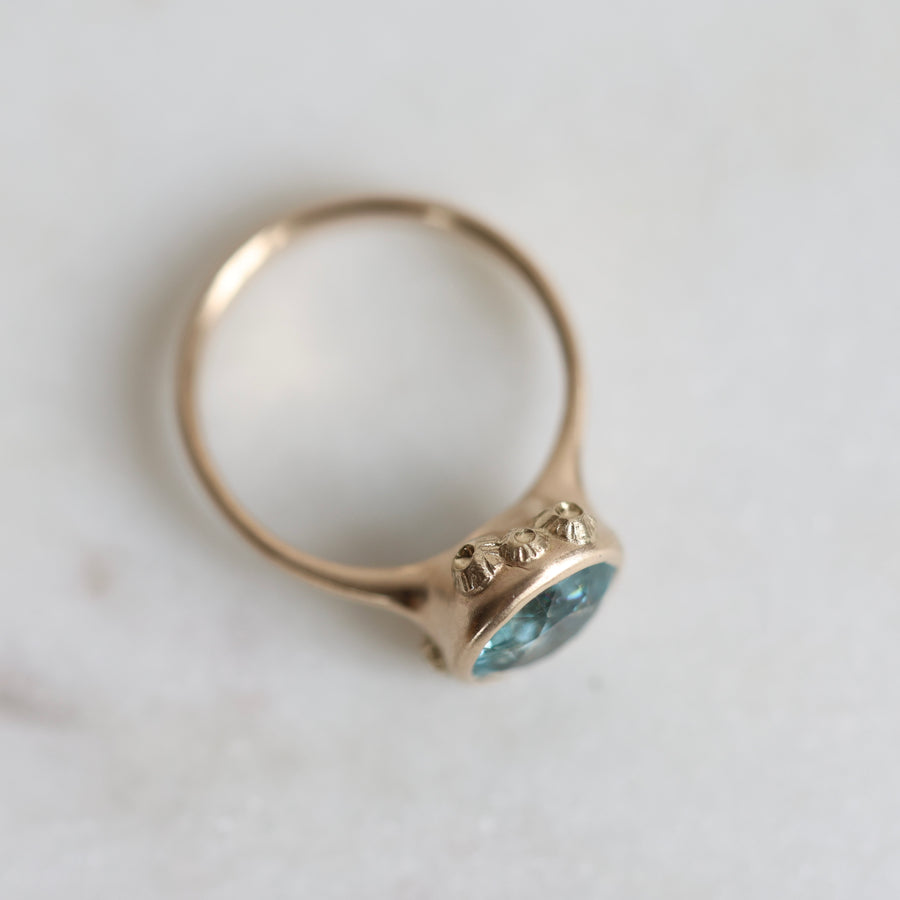 Gold ring with a blue gemstone on a light background