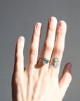 Hand with a ring and tattoo on a gray background