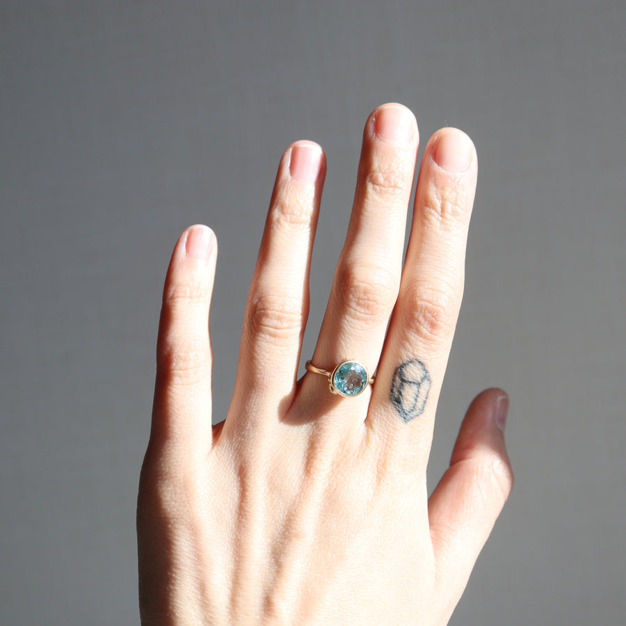 Hand with a ring and tattoo on a gray background