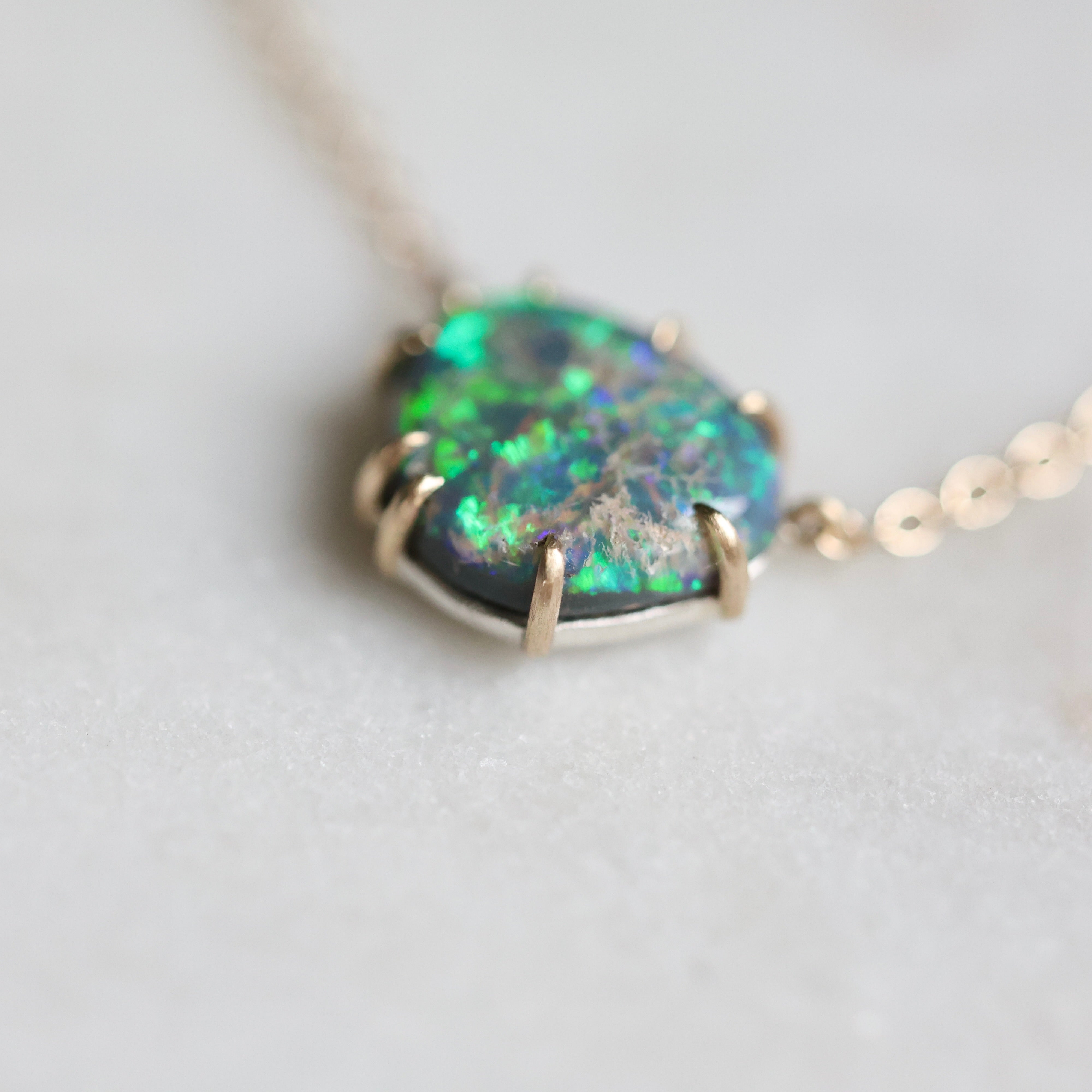 Necklace with a green opal pendant on a light gray background