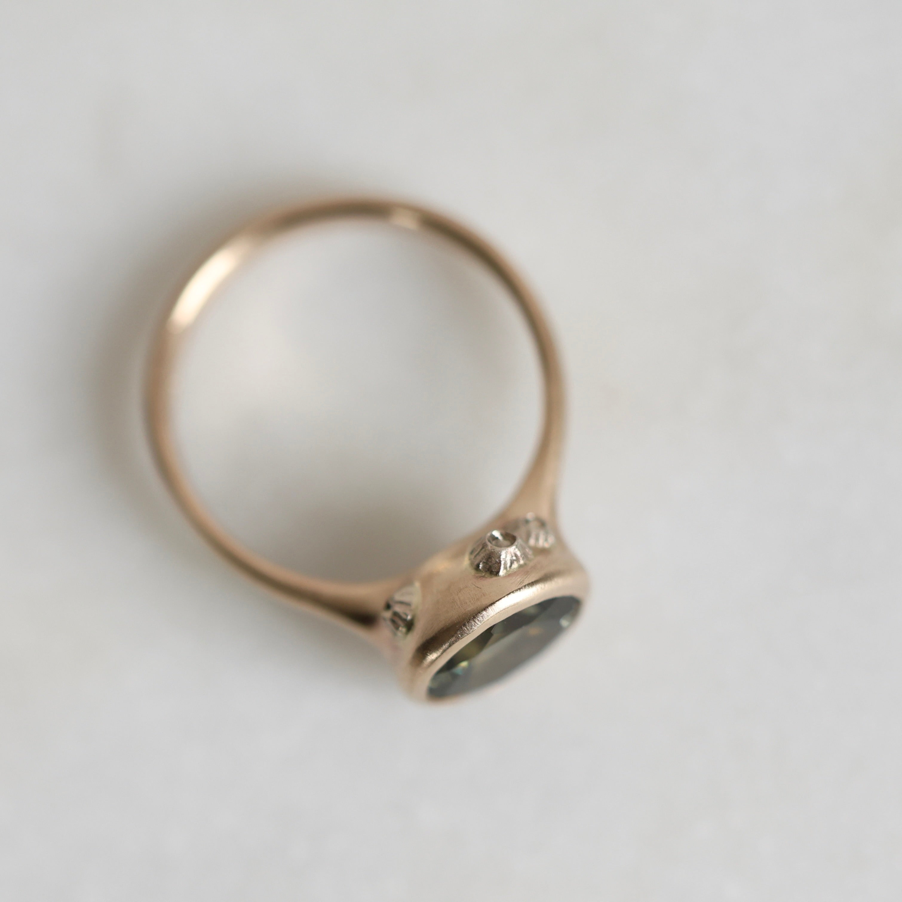 Gold ring with a green gemstone on a light gray background