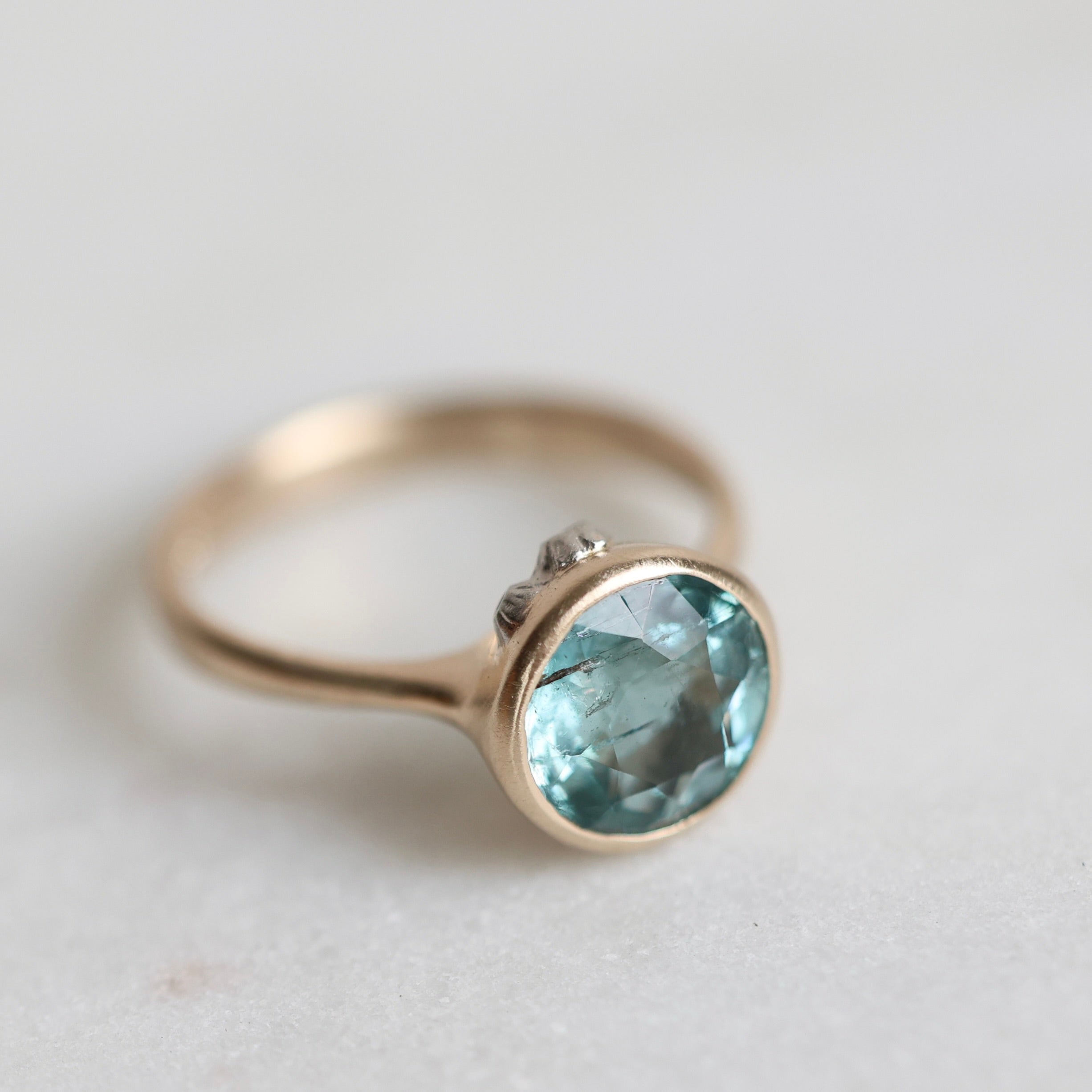 Gold ring with a blue gemstone on a light background