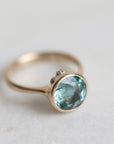 Gold ring with a blue gemstone on a light background