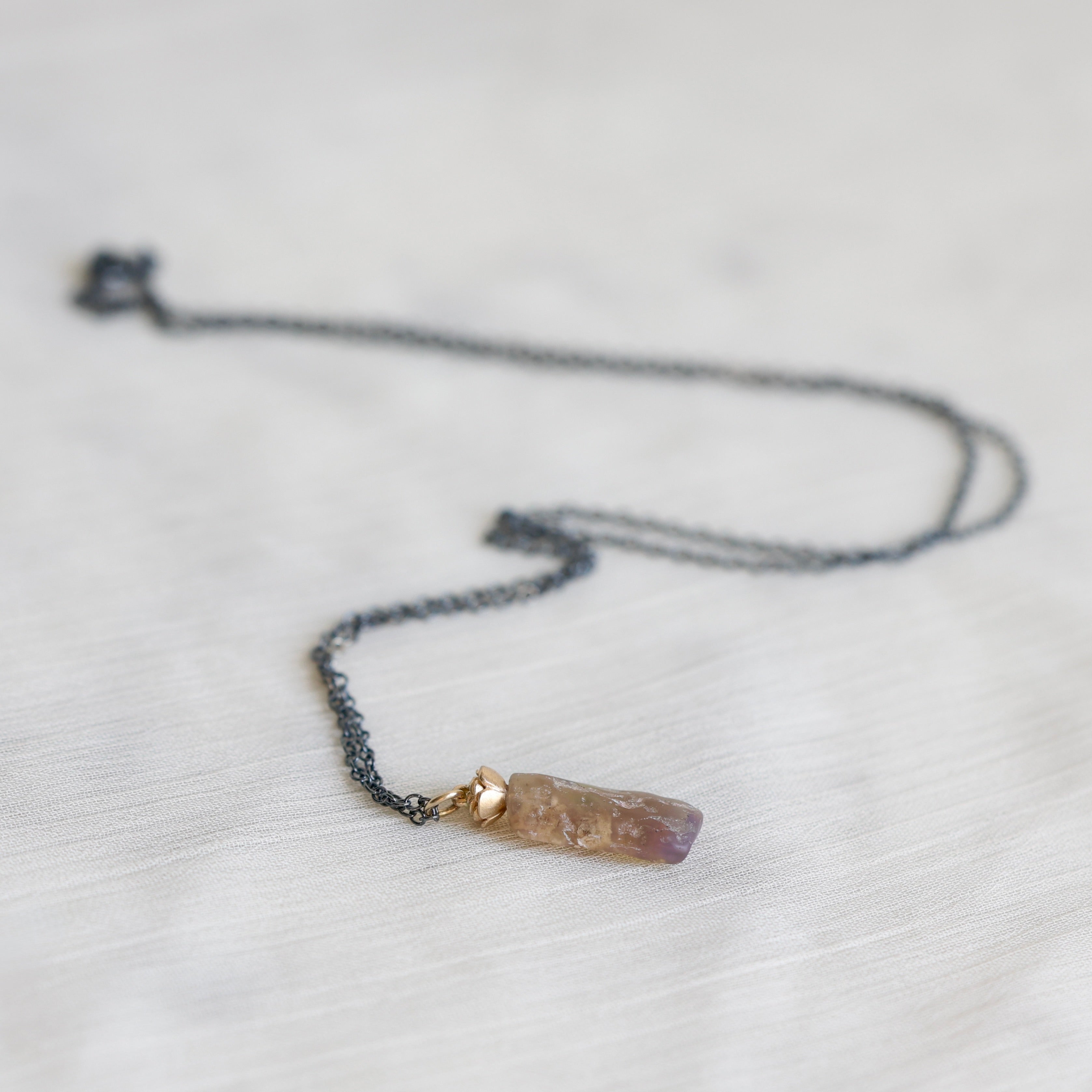 Necklace with an amber colored opal pendant on a light gray background