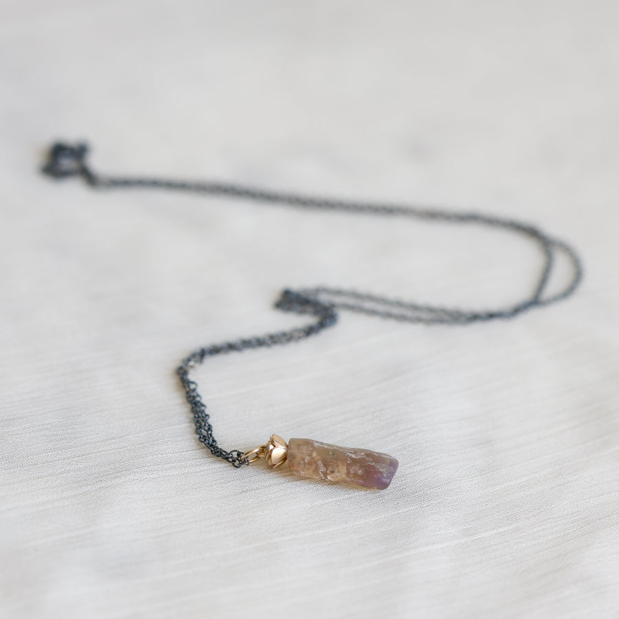 Necklace with an amber colored opal pendant on a light gray background