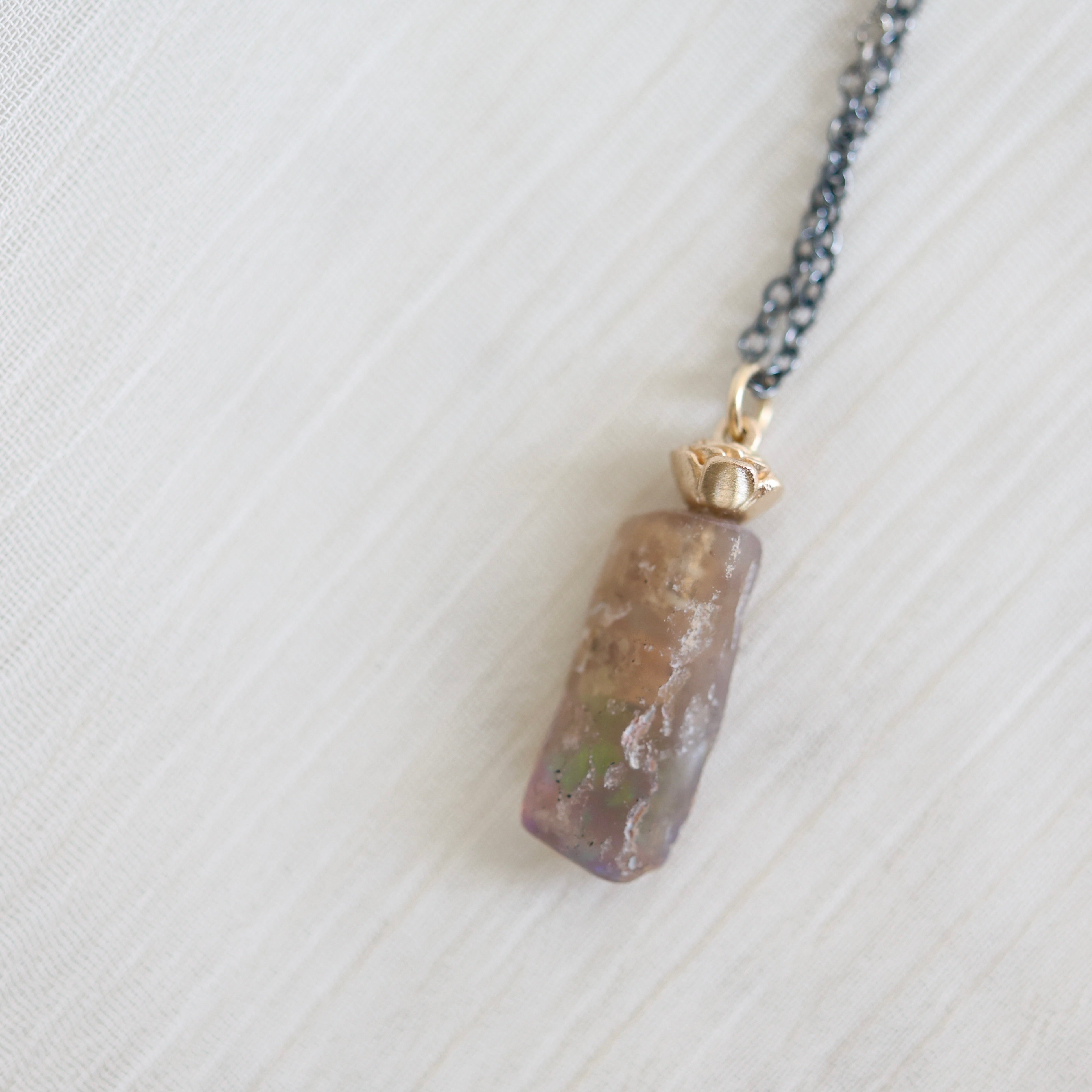 Necklace with an amber colored opal pendant on a light gray background