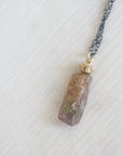 Necklace with an amber colored opal pendant on a light gray background