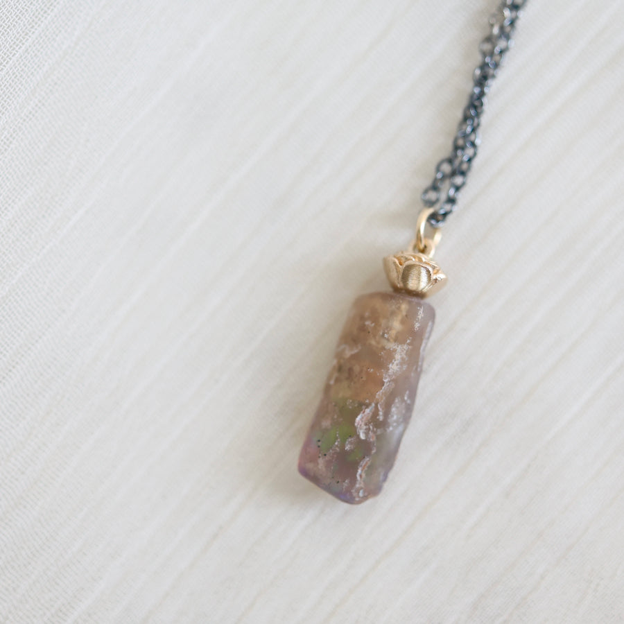 Necklace with an amber colored opal pendant on a light gray background