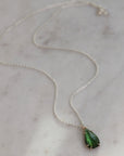 Green teardrop pendant necklace on a marble surface