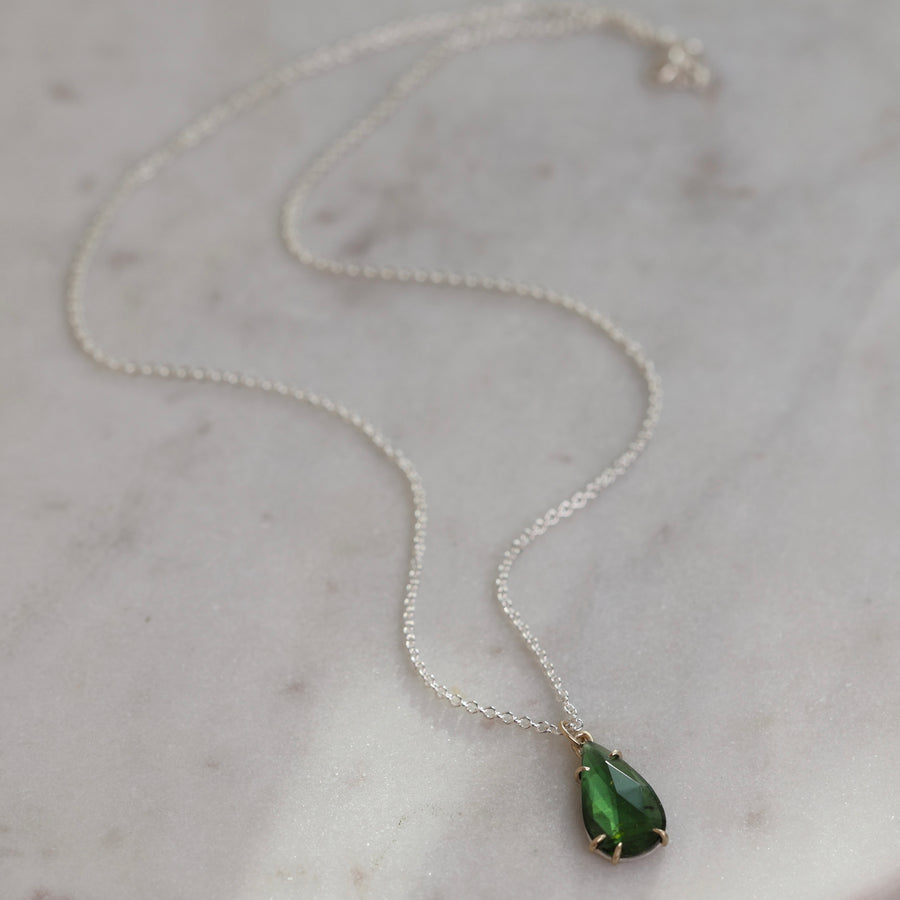 Green teardrop pendant necklace on a marble surface