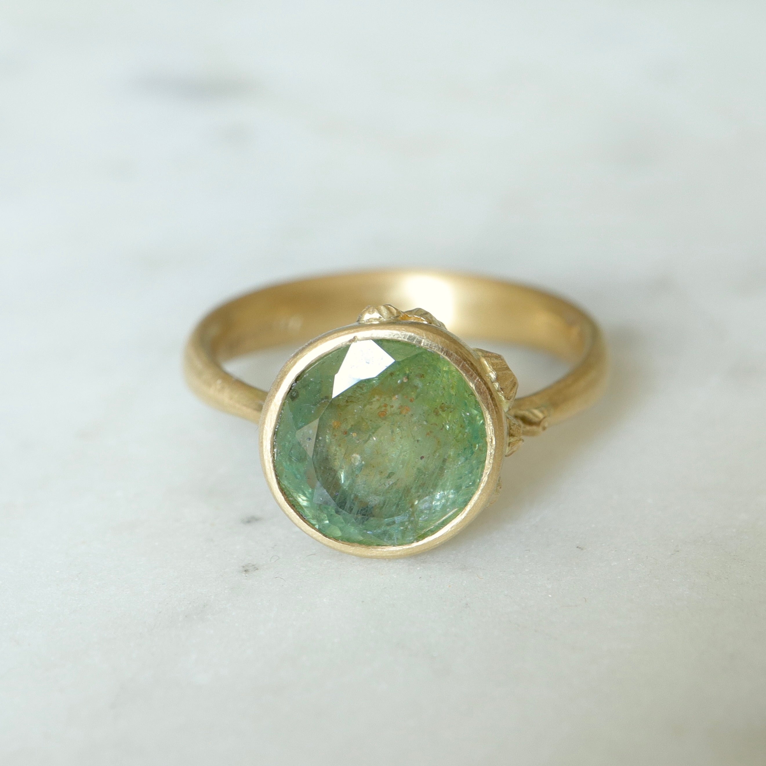 mossy green montana sapphire set in a gold ring with barnacles