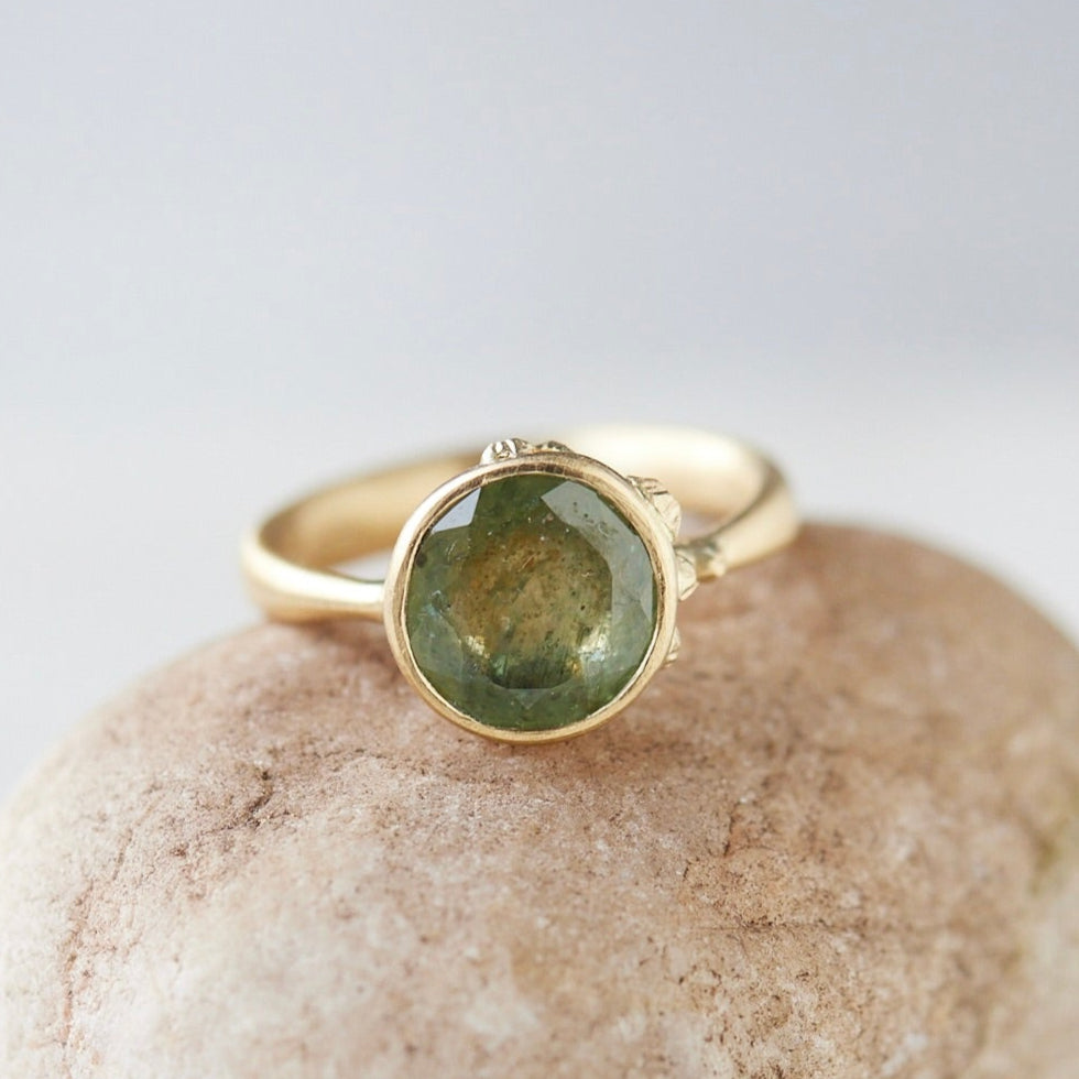 mossy green montana sapphire set in a gold ring with barnacles