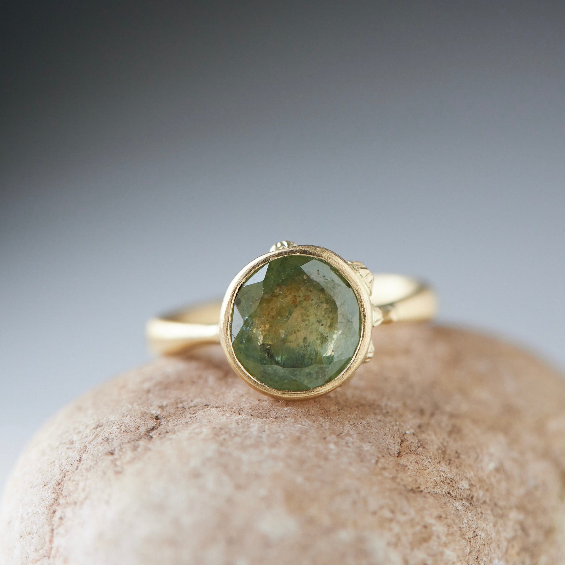 mossy green montana sapphire set in a gold ring with barnacles