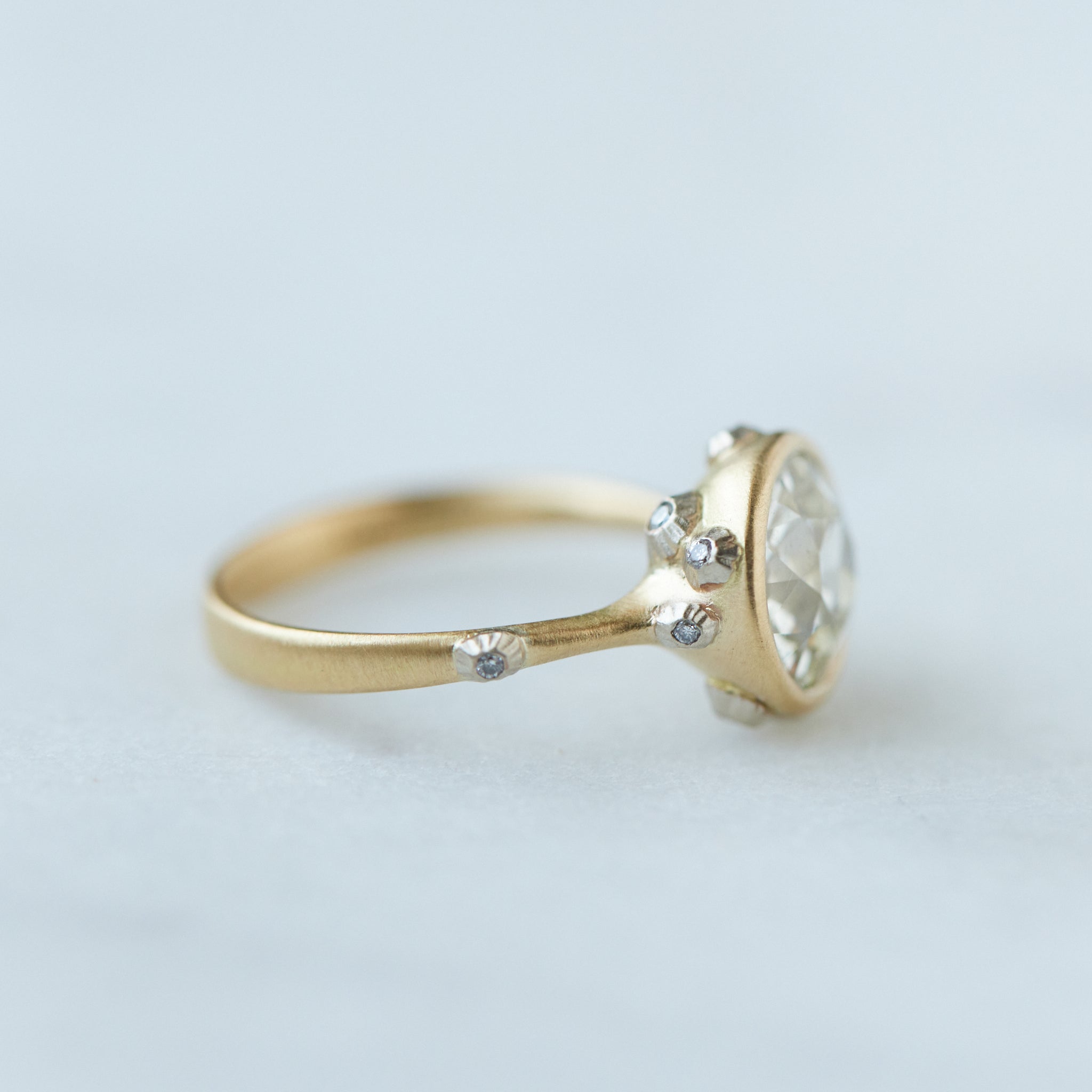 Diamond ring with gold bezel setting and white gold barnacles. THe barnacles have diamonds in them. Side profile.