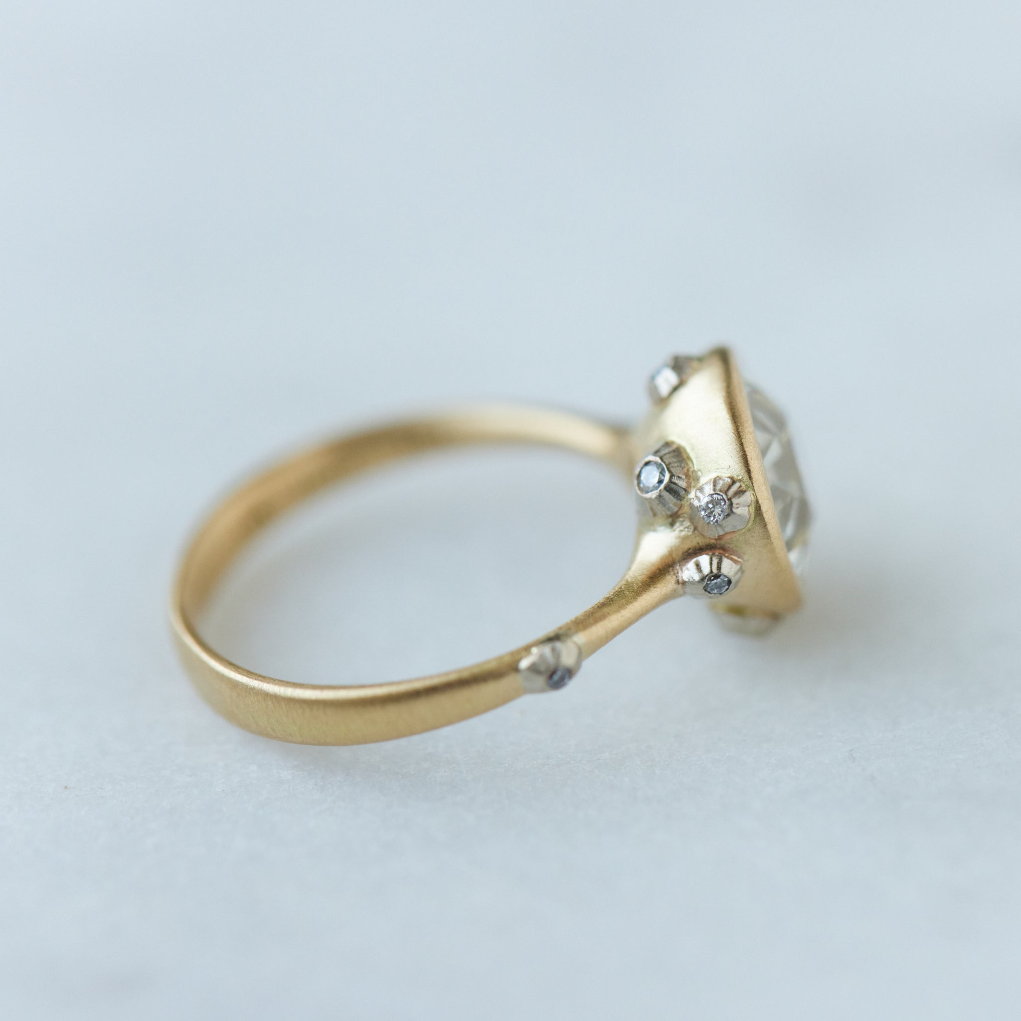 Diamond ring with gold bezel setting and white gold barnacles. THe barnacles have diamonds in them. Side view.