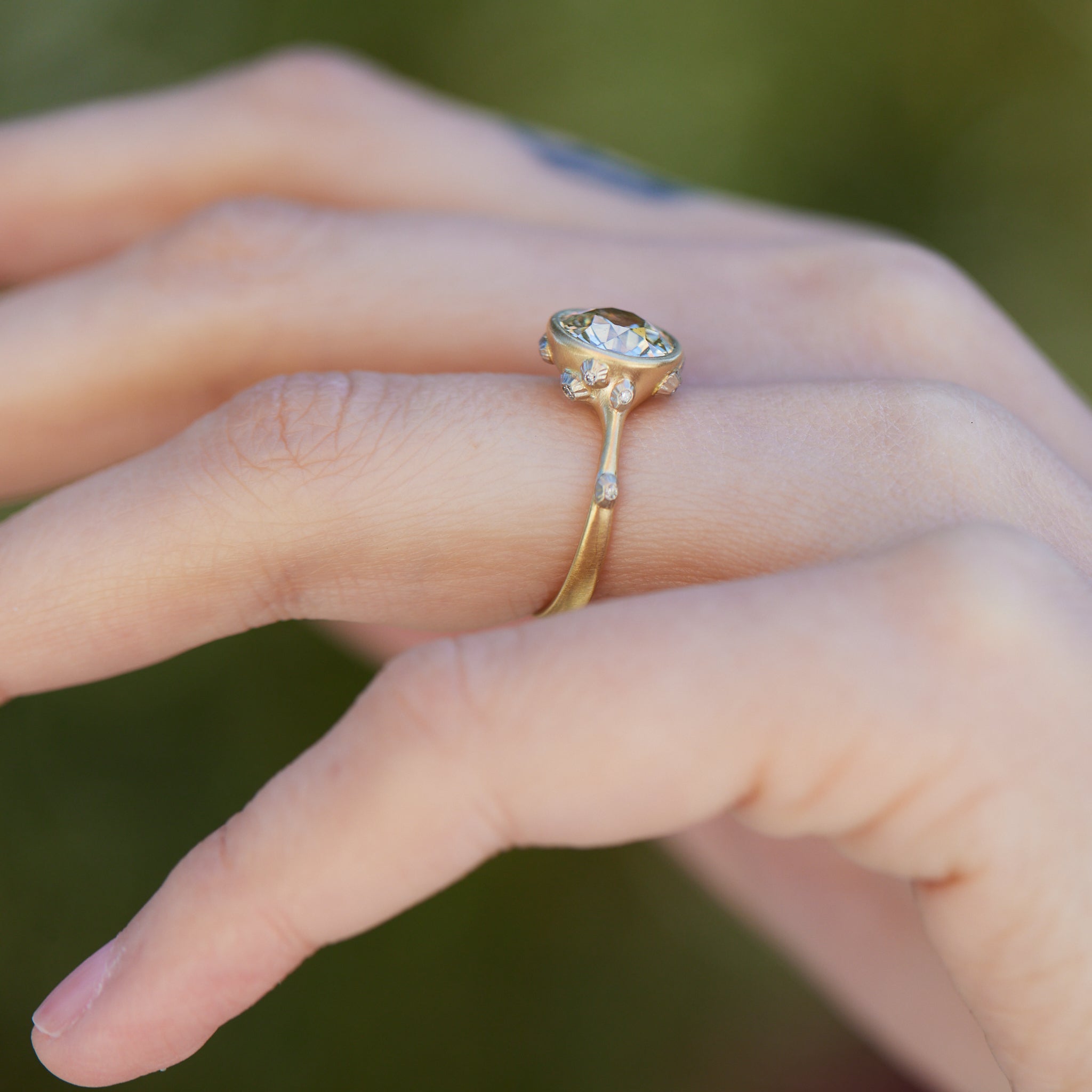 Diamond ring with gold bezel setting and white gold barnacles. The barnacles have diamonds in them. Shown on person.
