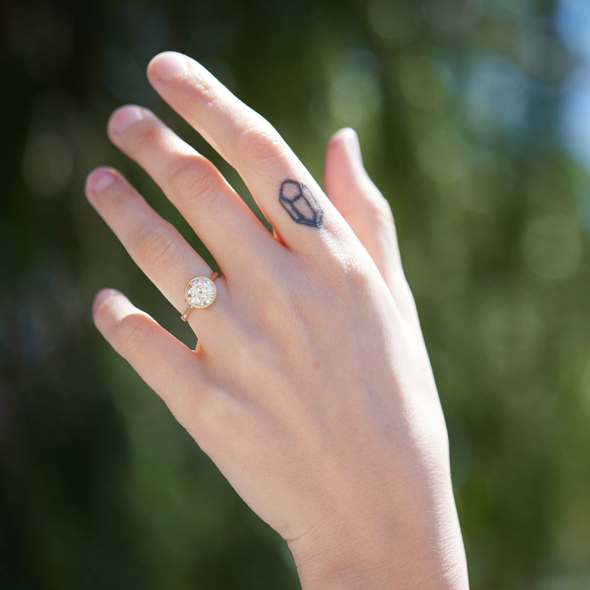 Diamond ring with gold bezel setting and white gold barnacles. THe barnacles have diamonds in them. On person.