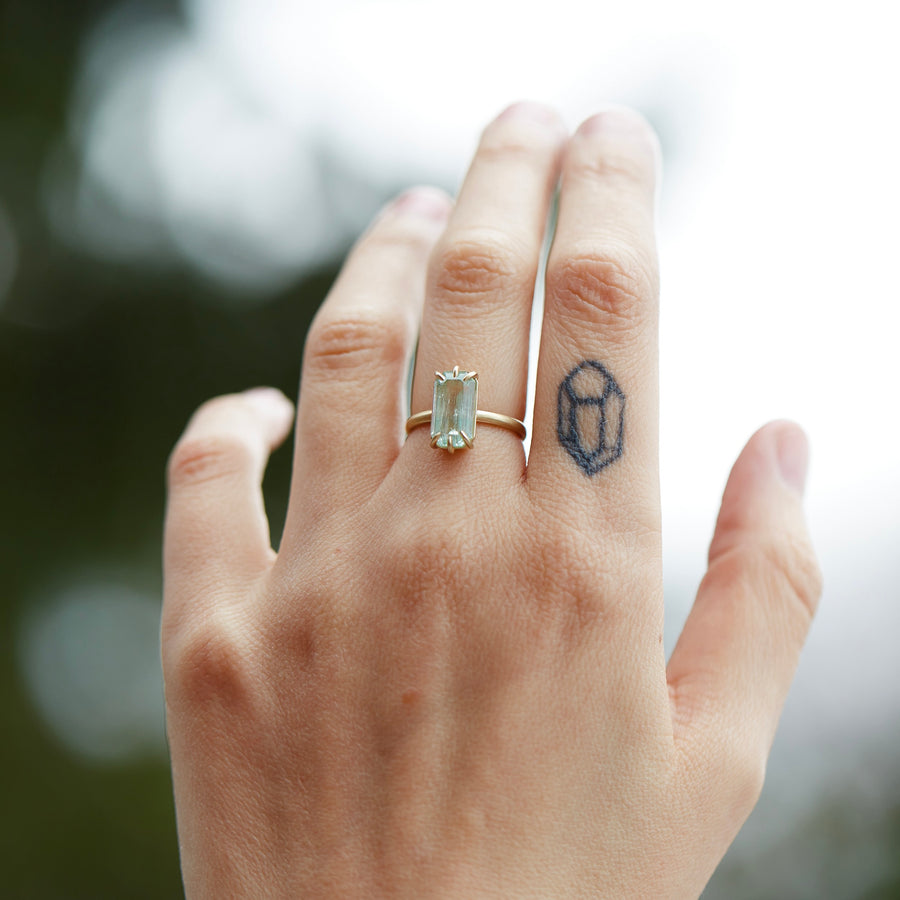 Emerald ring with gold prongs on hand