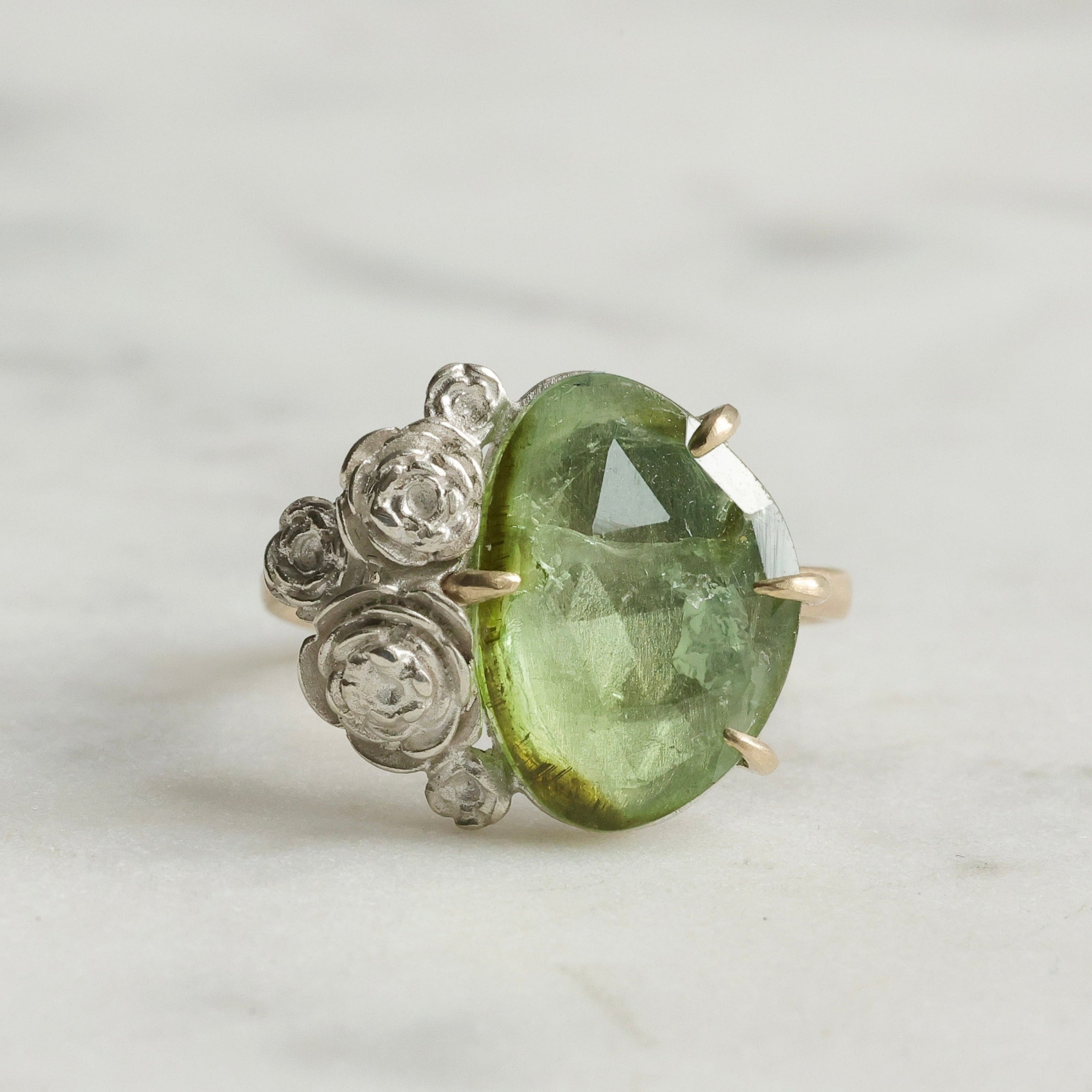3.02ct mossy green tourmaline ring with 14k yellow gold prongs and band and bright sterling silver stone seat and rose accents.