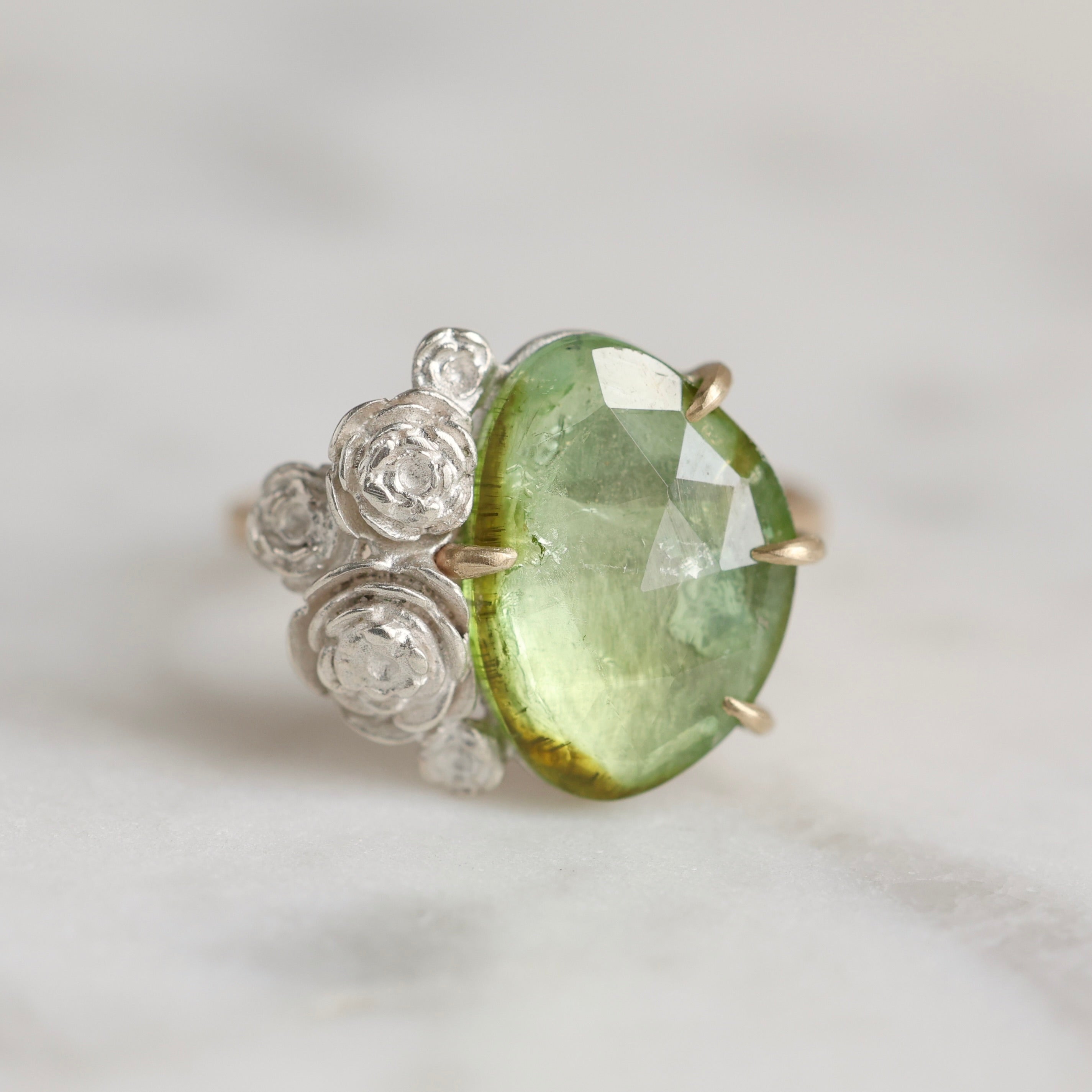 Side View: 3.02ct mossy green tourmaline ring with 14k yellow gold prongs and band and bright sterling silver stone seat and rose accents.