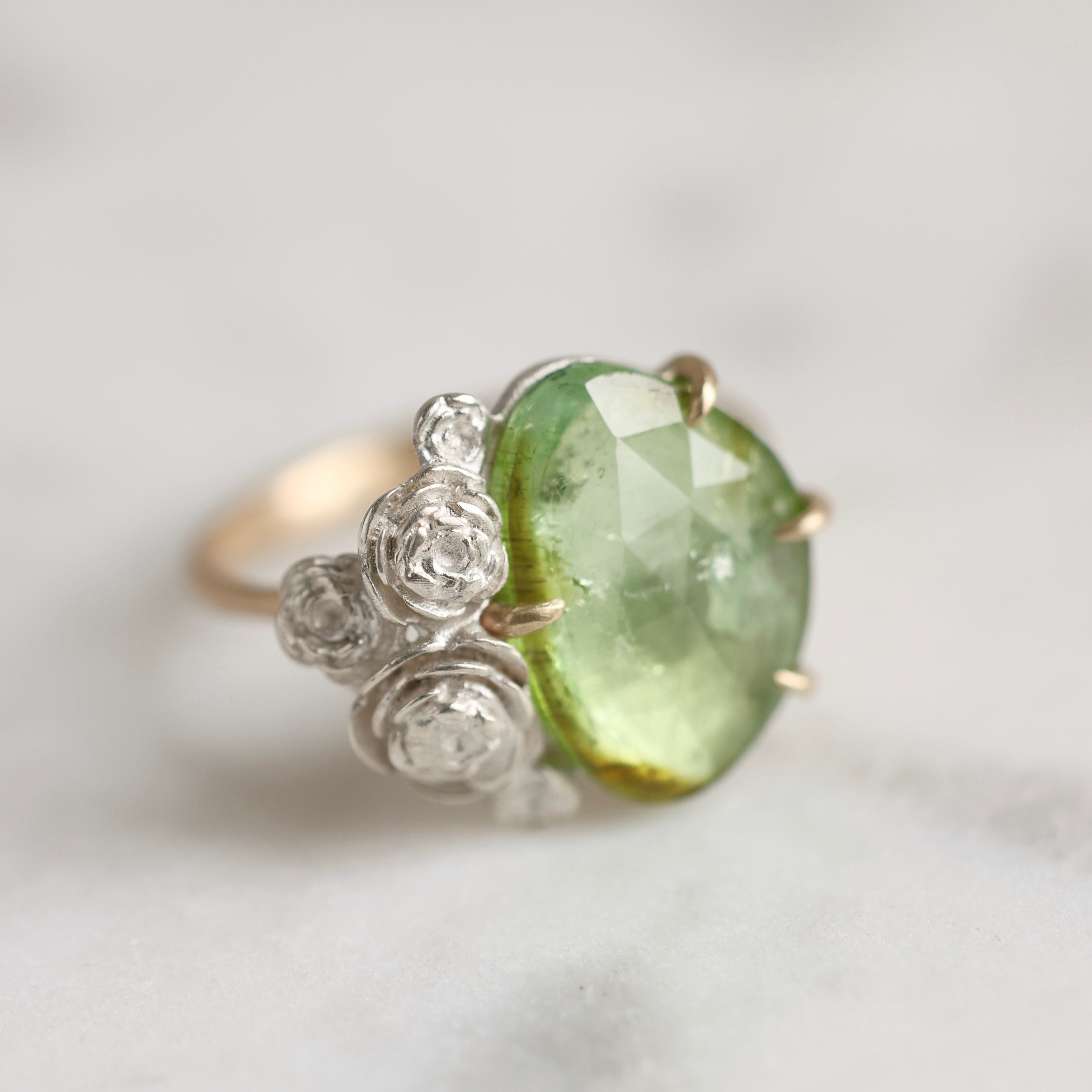 Side view: 3.02ct mossy green tourmaline ring with 14k yellow gold prongs and band and bright sterling silver stone seat and rose accents.
