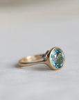 gold ring with a blue gemstone on a light gray background