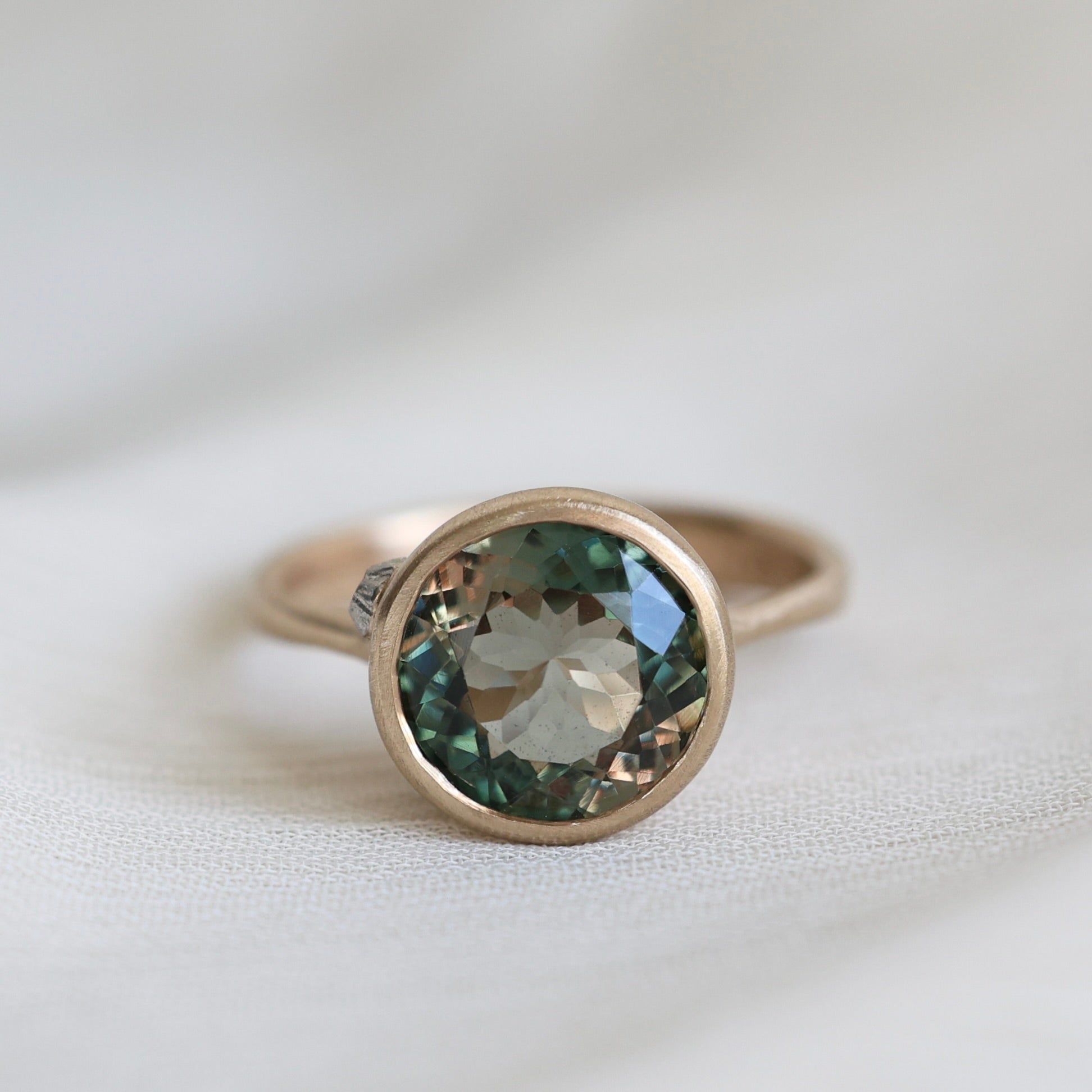 Ring with a green gemstone on a light fabric background