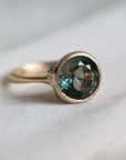 Gold ring with a green gemstone on a light fabric background