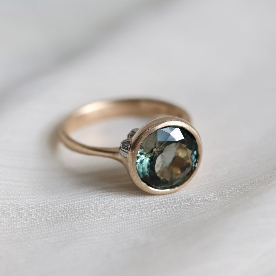 Gold ring with a green gemstone on a light fabric background