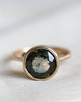 Gold ring with a dark gemstone on a light fabric background