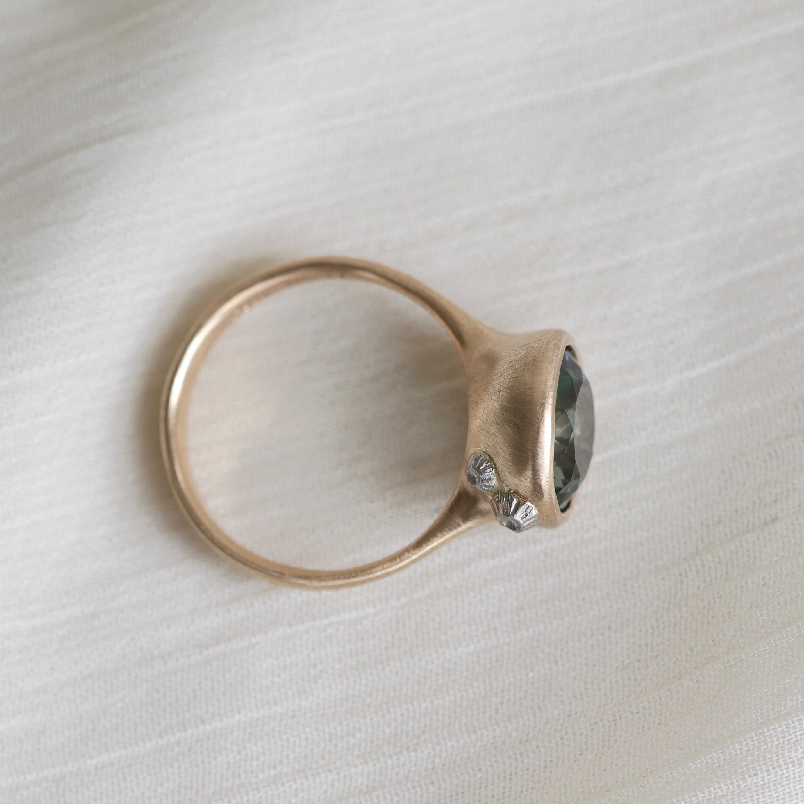 Gold ring with a gemstone on a light fabric background