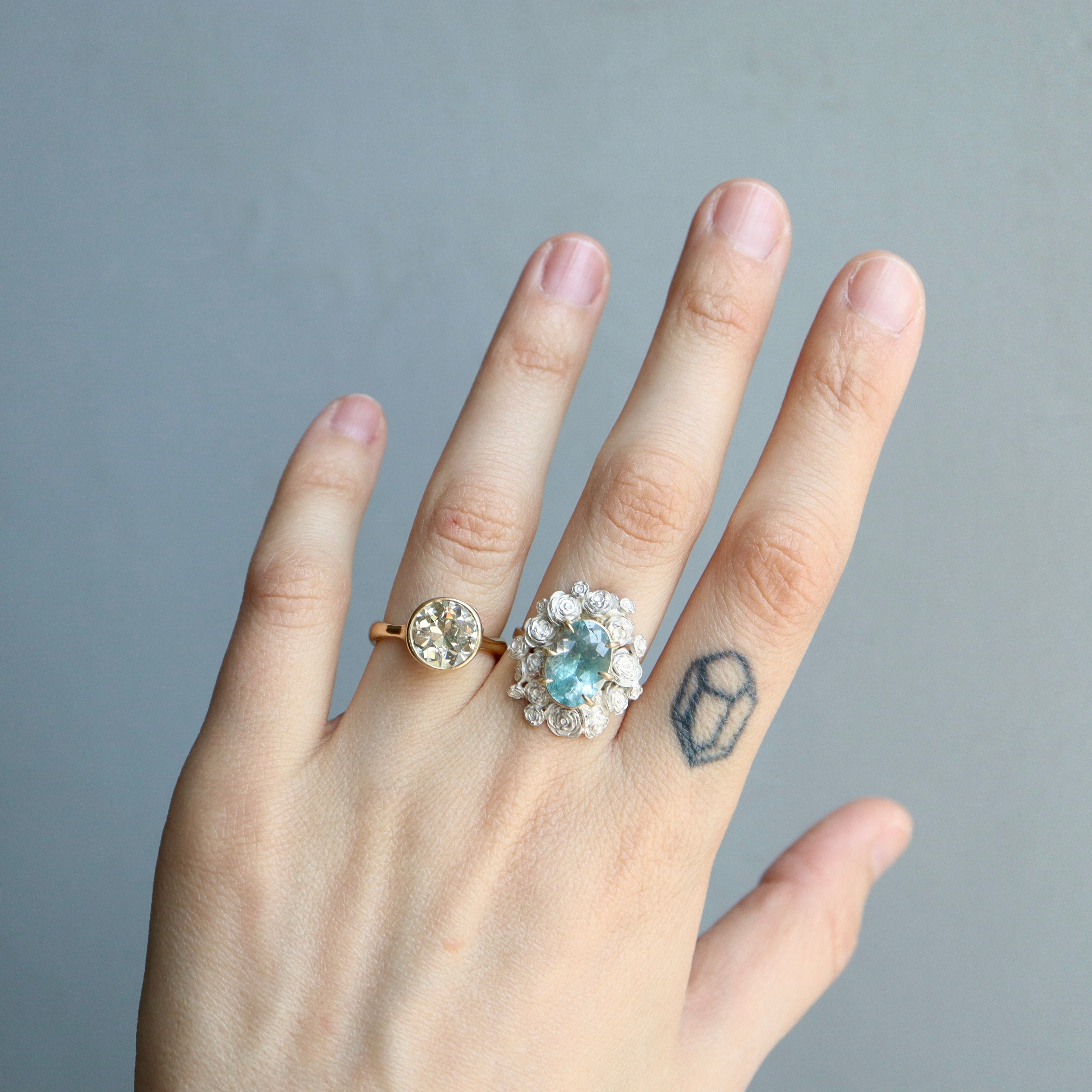A ring with a wreath of silver roses around a pale blue tourmaline stone