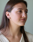 Woman wearing a gold earring against a plain background