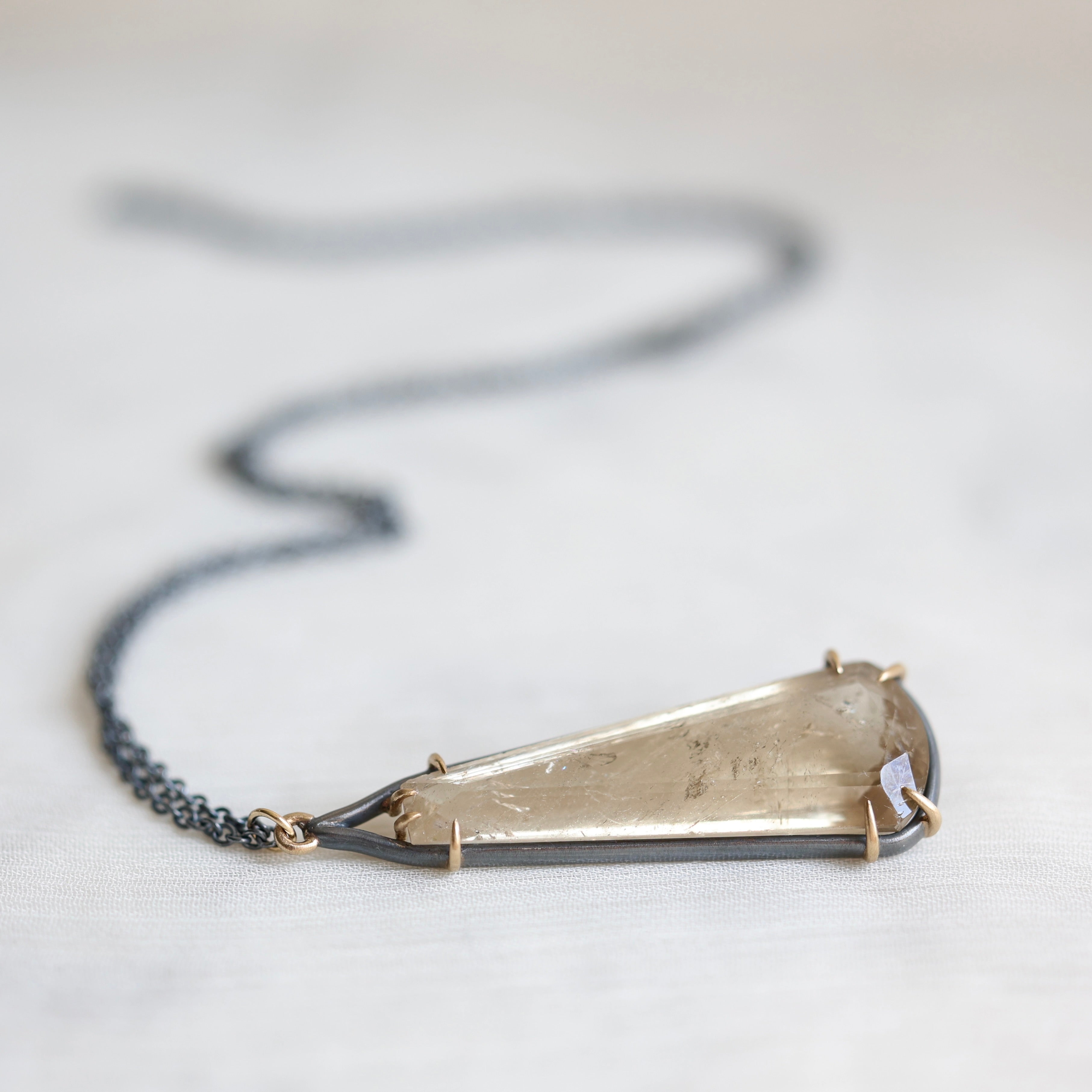 Necklace with a large, geometric pendant on a light background