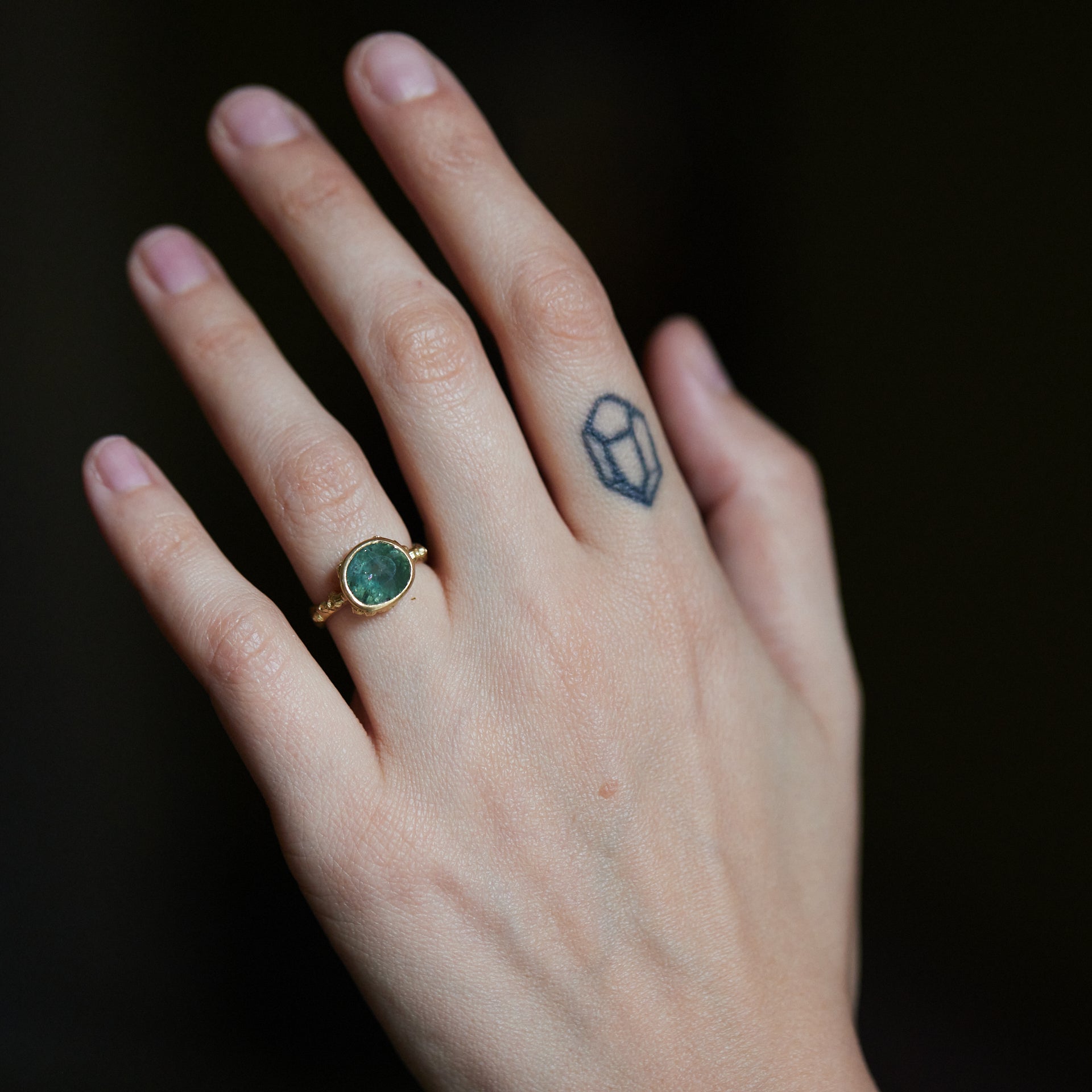 pale teal montana sapphire set in yellow gold ring with barnacles- on person