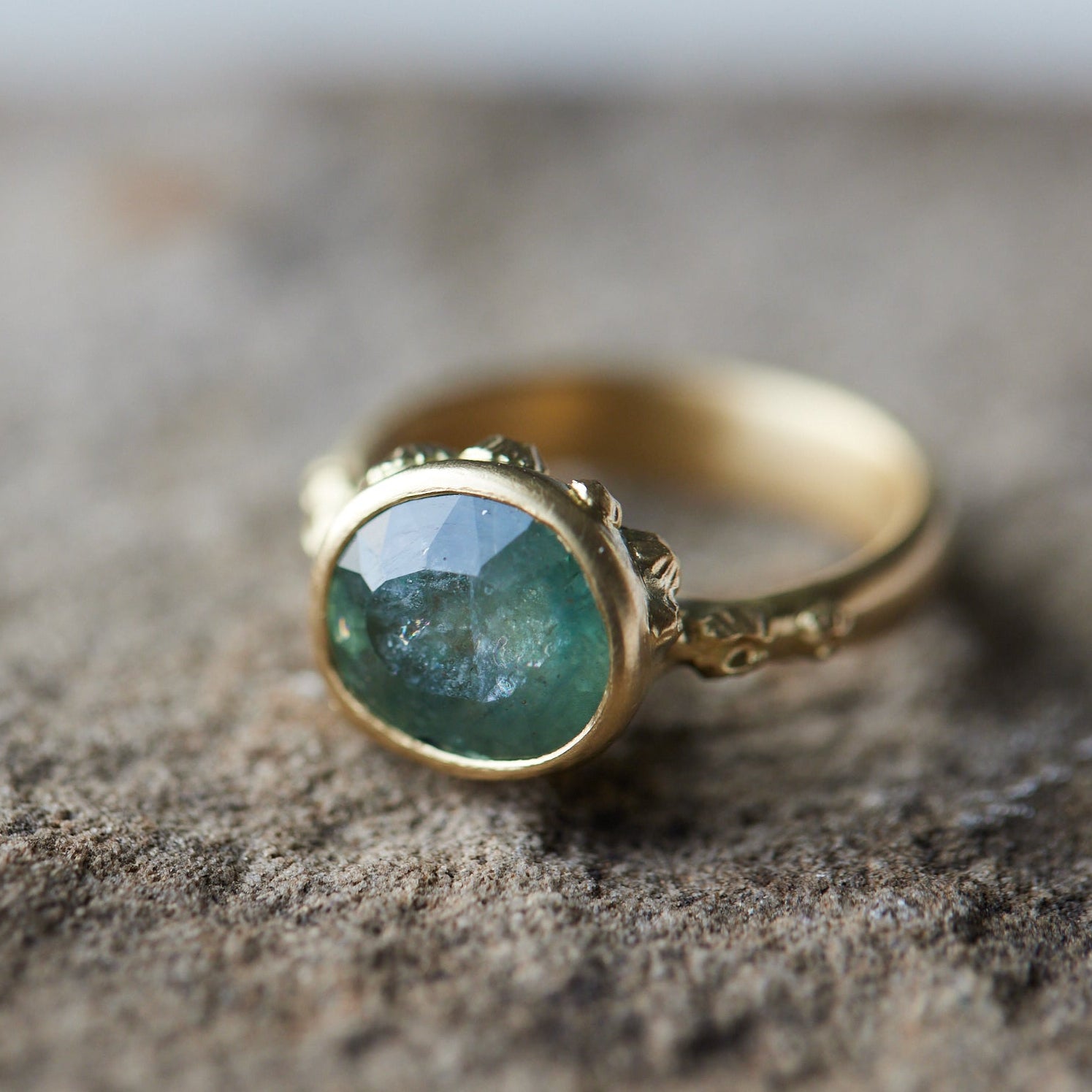 natural light on pale teal montana sapphire set in yellow gold ring with barnacles