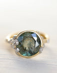 Gold ring with a green gemstone and barnacles on a light background