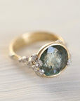 Gold ring with a green gemstone and barnacles on a light background