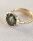 Gold ring with a green gemstone and barnacles on a light background